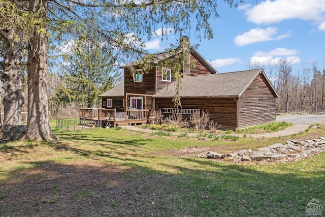 rear view of property with a lawn, a chimney, a shingled roof, and a deck
