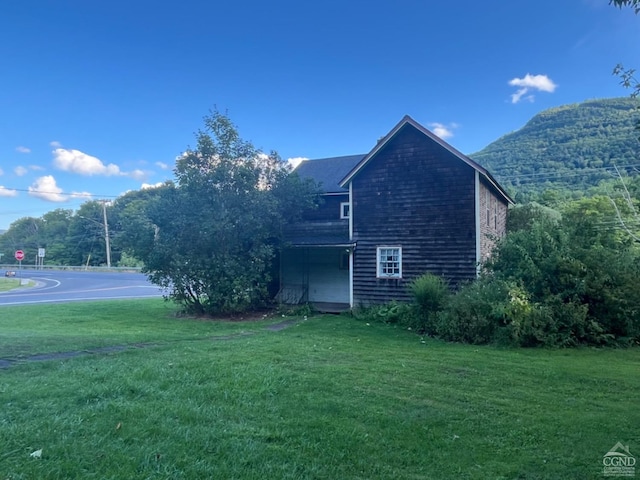 view of side of home featuring a lawn and a mountain view