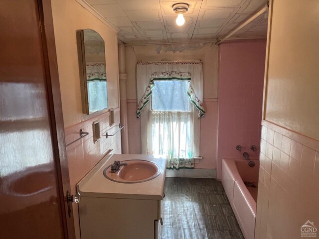 bathroom featuring shower / bathtub combination, vanity, and tile walls