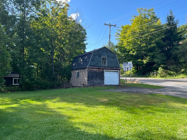 view of side of home with a lawn, a garage, and an outbuilding