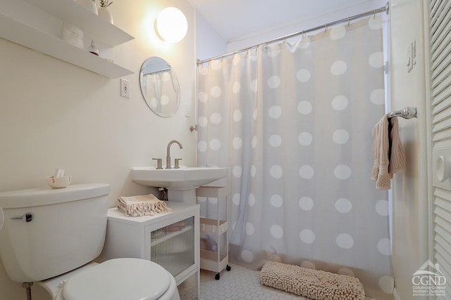 bathroom featuring toilet, a shower with curtain, a sink, and tile patterned floors