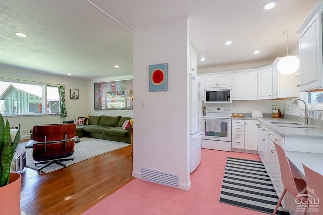 kitchen featuring a sink, light countertops, white appliances, and white cabinetry