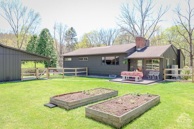 rear view of house with fence, roof with shingles, a chimney, and a vegetable garden