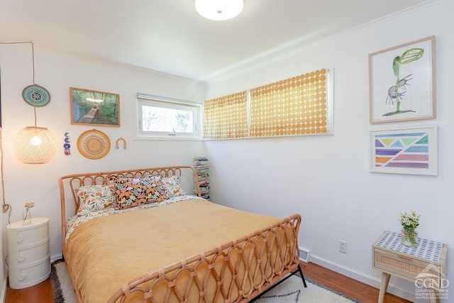 bedroom with baseboards, wood finished floors, and visible vents