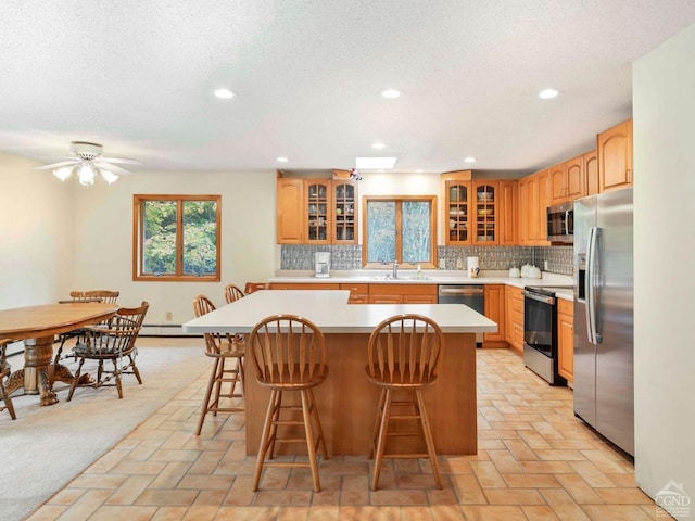 kitchen featuring a kitchen bar, a center island, stainless steel appliances, and sink