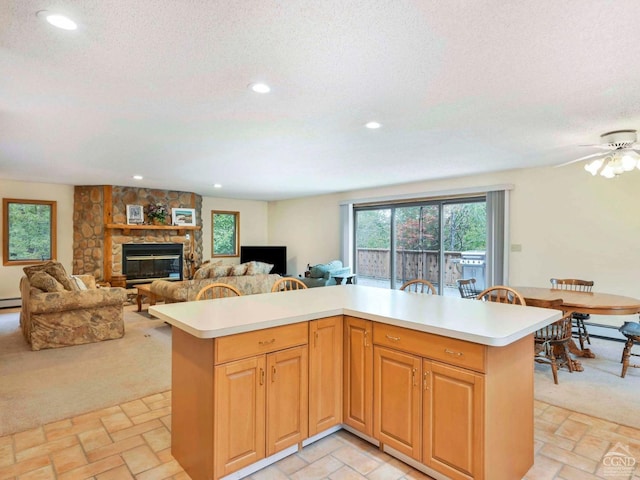 kitchen with a fireplace, a textured ceiling, a center island, and ceiling fan