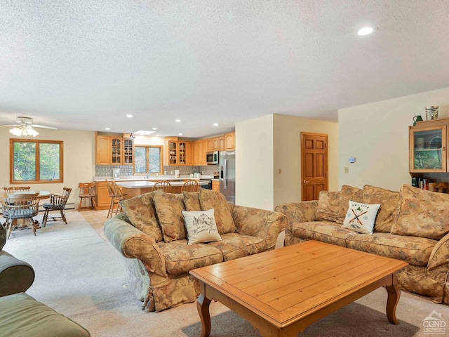 living room with a textured ceiling, light colored carpet, and ceiling fan