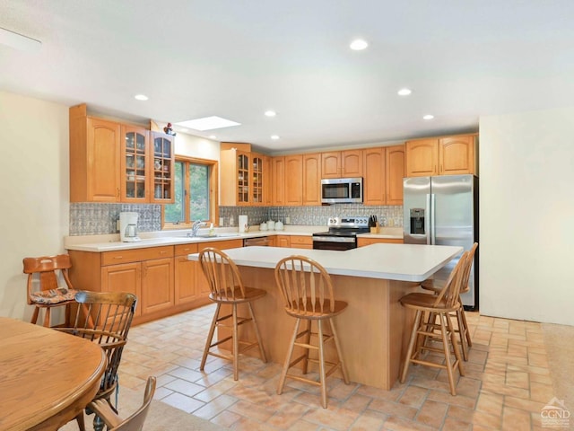 kitchen with a breakfast bar, a kitchen island, appliances with stainless steel finishes, and a skylight