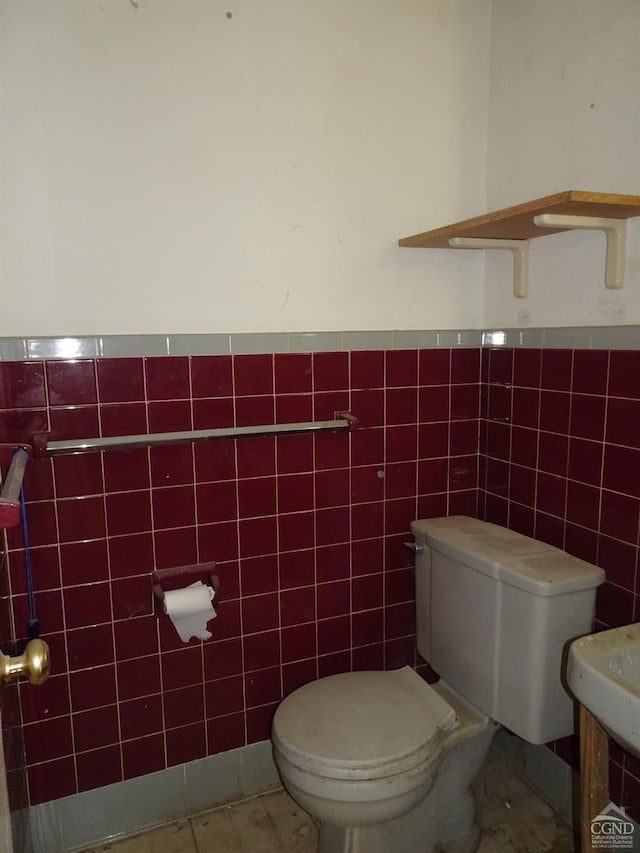 half bathroom with tile walls, a wainscoted wall, and toilet