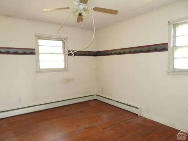 empty room featuring a baseboard heating unit, a ceiling fan, and wood finished floors