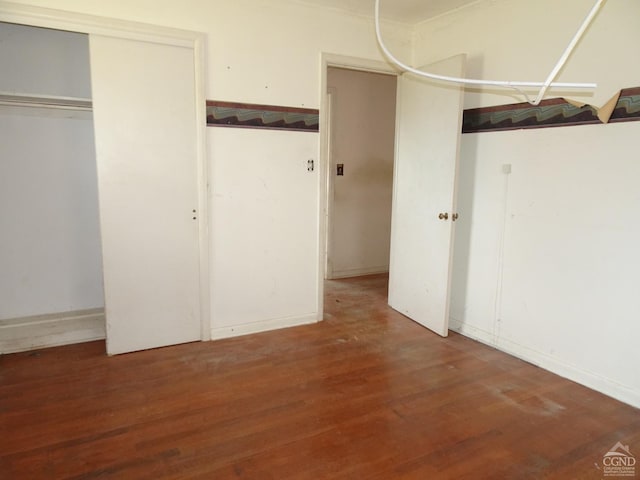 unfurnished bedroom with wood finished floors and a closet
