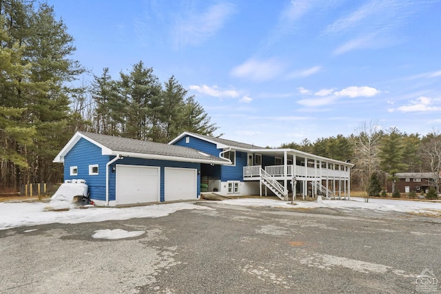 view of front facade featuring roof with shingles, stairway, and an attached garage