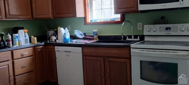 kitchen featuring brown cabinetry, white appliances, and a sink