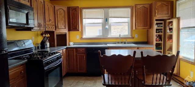 kitchen featuring a sink, black appliances, a kitchen island, and a healthy amount of sunlight