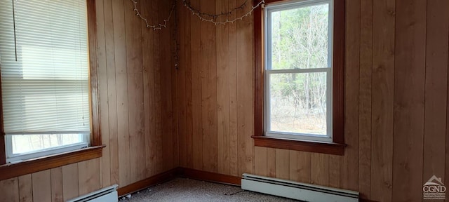 spare room featuring wood walls and a baseboard radiator