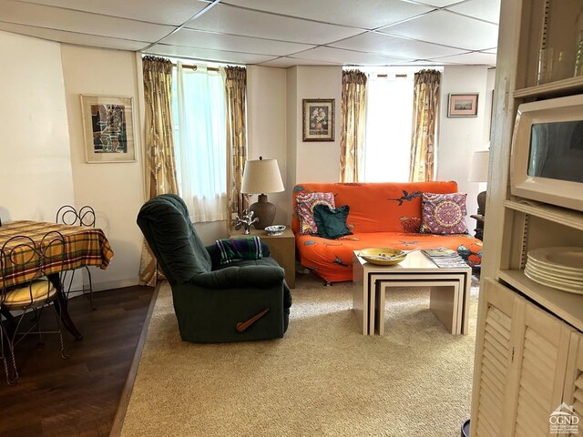 living area with a drop ceiling and dark wood-type flooring