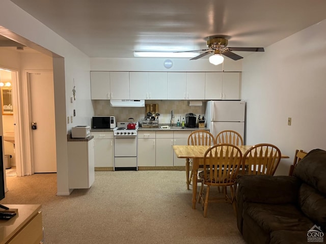 kitchen with tasteful backsplash, white appliances, ventilation hood, sink, and white cabinets