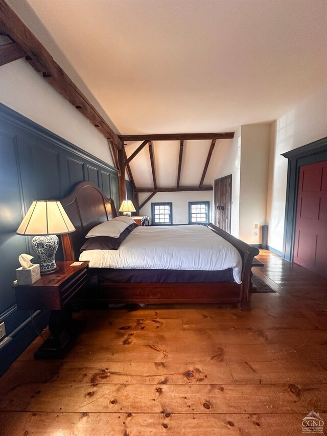 bedroom featuring lofted ceiling with beams and hardwood / wood-style flooring