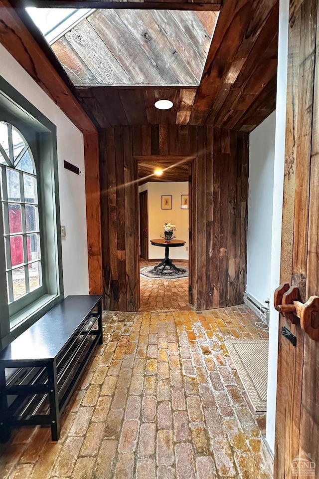 corridor with baseboard heating, wood walls, and wooden ceiling