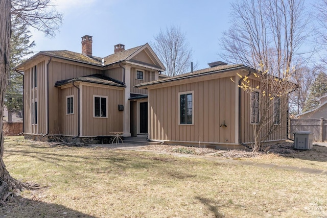 rear view of property featuring fence, a chimney, and a lawn