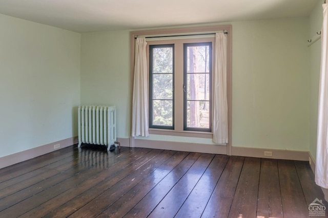 empty room featuring dark wood-style flooring, baseboards, and radiator heating unit