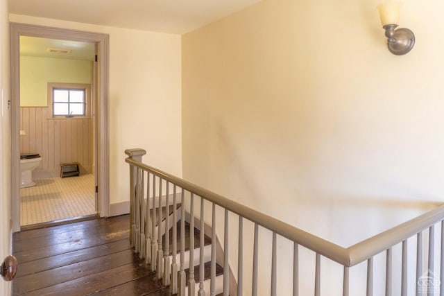 stairs featuring wood-type flooring and a wainscoted wall