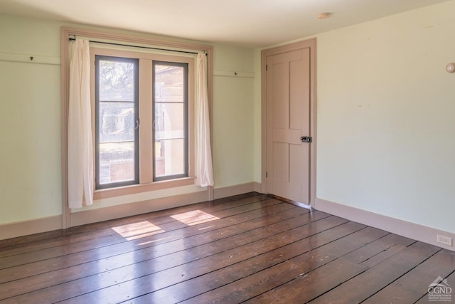 unfurnished room with baseboards and wood-type flooring