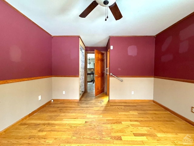 empty room featuring light wood-type flooring, ceiling fan, and crown molding