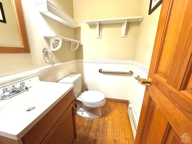 bathroom with hardwood / wood-style flooring, baseboard heating, toilet, and vanity