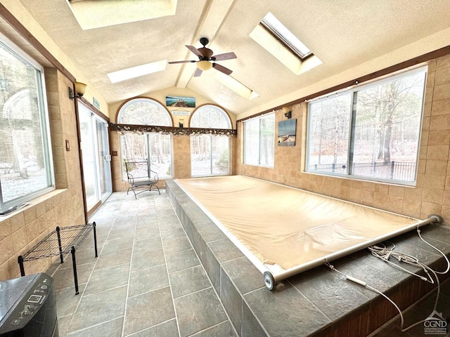 game room with ceiling fan, tile patterned flooring, and lofted ceiling with skylight