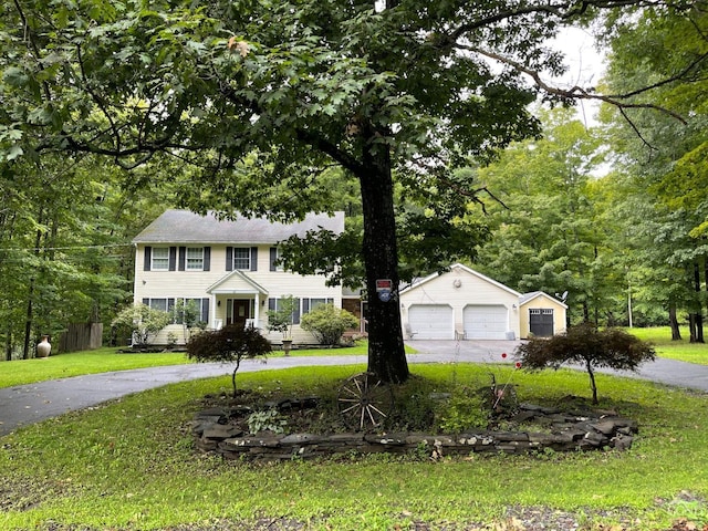 colonial-style house with an outbuilding, a front lawn, and a garage