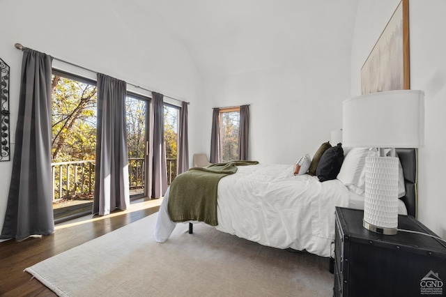 bedroom featuring dark hardwood / wood-style floors, access to exterior, high vaulted ceiling, and multiple windows