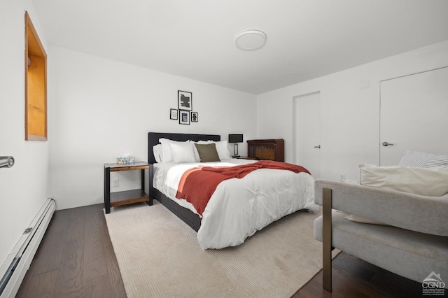 bedroom with wood-type flooring and a baseboard heating unit