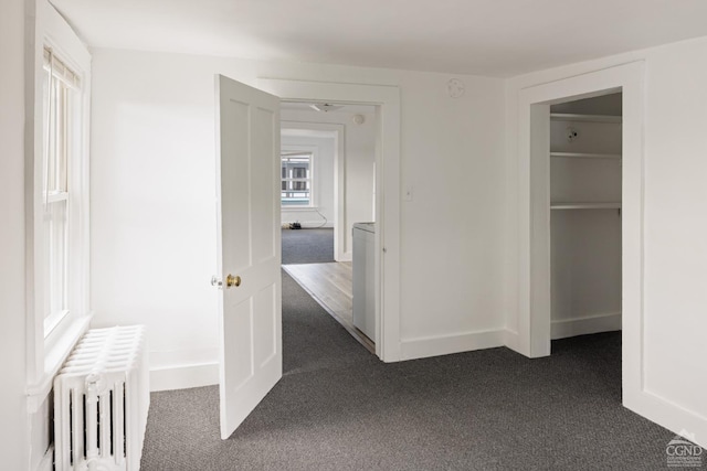 hallway with radiator heating unit and dark colored carpet