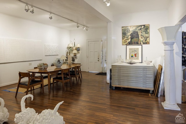 dining space with dark hardwood / wood-style flooring, ornamental molding, rail lighting, and decorative columns