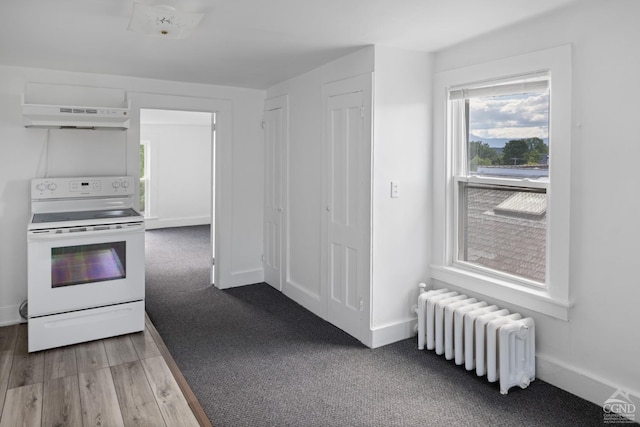 kitchen featuring radiator heating unit, white electric range oven, range hood, white cabinets, and hardwood / wood-style flooring