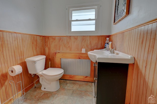 bathroom featuring vanity, toilet, and wood walls