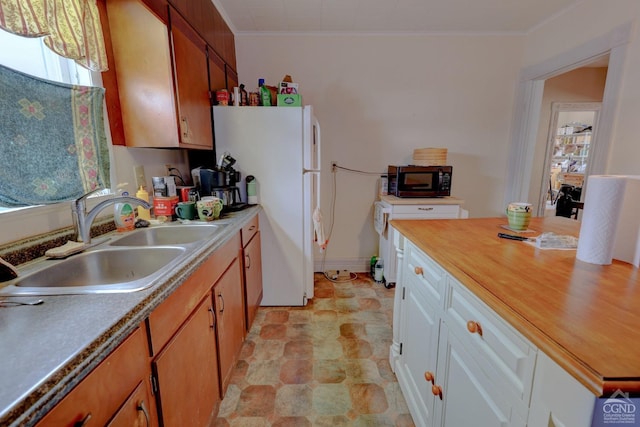 kitchen featuring white cabinets, white refrigerator, butcher block countertops, and sink