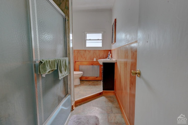 full bathroom with vanity, toilet, wooden walls, and bath / shower combo with glass door