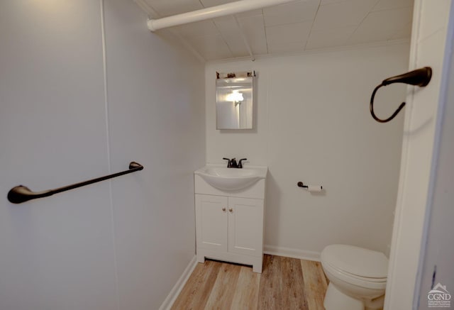 bathroom featuring vanity, toilet, wood-type flooring, and ornamental molding