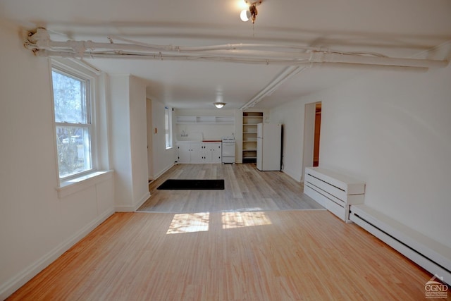 unfurnished room with light hardwood / wood-style floors and a baseboard heating unit