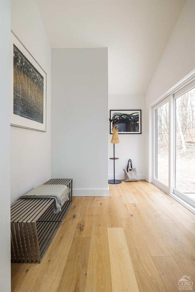 unfurnished room featuring baseboards, hardwood / wood-style floors, and lofted ceiling