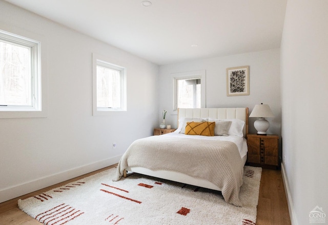 bedroom with baseboards, multiple windows, and wood finished floors