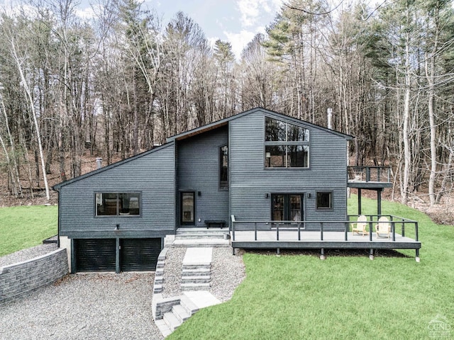 rear view of house featuring a yard, a deck, and an attached garage