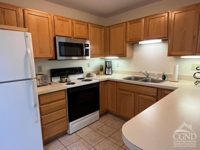 kitchen featuring sink, light tile patterned flooring, and white appliances