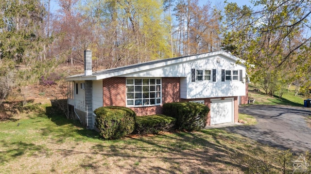 view of home's exterior featuring a yard, a garage, aphalt driveway, and brick siding
