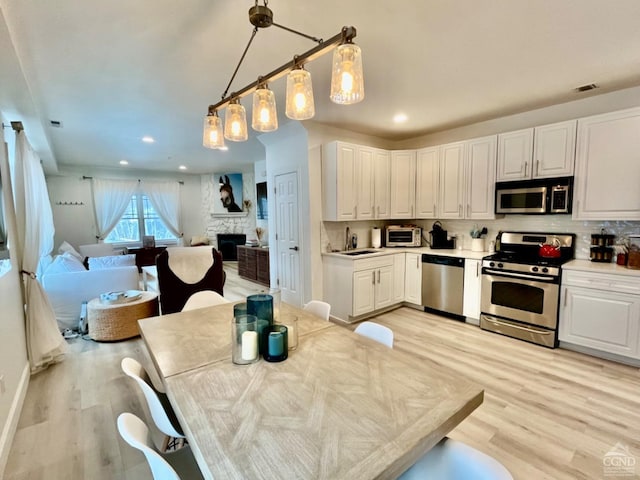 kitchen featuring white cabinetry, stainless steel appliances, and hanging light fixtures