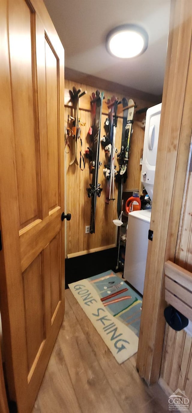 interior space featuring laundry area, wooden walls, wood finished floors, and stacked washing maching and dryer