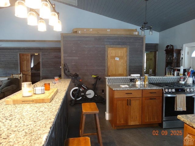 kitchen featuring light stone counters, decorative light fixtures, vaulted ceiling, and gas stove