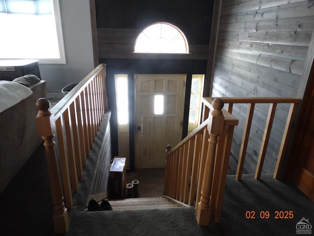 carpeted foyer featuring wood walls